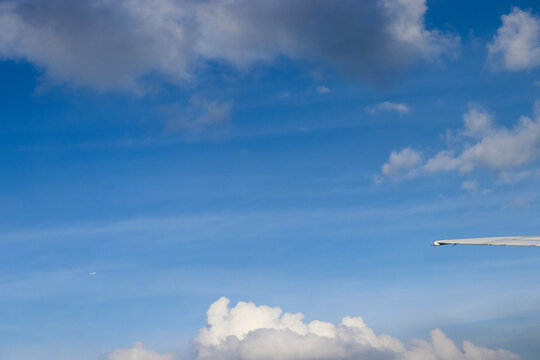 Aerial View of Urban Landscape with Airplane Wing Under Clear Blue Sky and Scattered Clouds