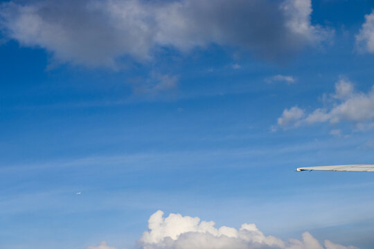 Aerial View of Urban Landscape with Airplane Wing Under Clear Blue Sky and Scattered Clouds