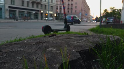 Urban scene at dusk with electric scooter and tree stump, blending modern transportation and nature
