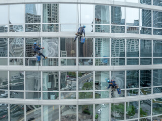 Professional alpinist window washers hang from a building in a harness and wash the large windows on an office building in Chicago
