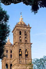 view of the tower of the metropolitan cathedral of Puebla framed with trees.