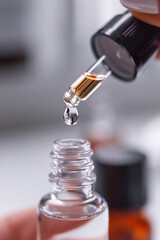 Close-up of a dropper dispensing a single drop of clear liquid into a glass bottle, with a clean, minimalistic background.