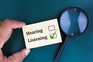 magnifying glass and paper with the words HEARING and LISTENING, select listening .concept of...