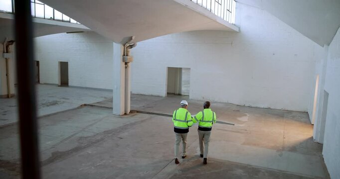 Construction, planning and men with discussion in warehouse for property, management or feedback. Top view, contractor and people with walking on site for civil engineering, project and communication