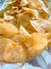 Lots of chips. Potato chips on foil. Junk food is chips.