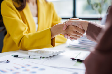 Two diverse professional business women executive leaders shaking hands at office meeting