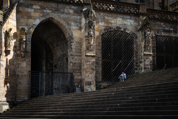 Ein Mann sitzt auf der Treppe des Doms in Erfurt im Schatten und telefoniert