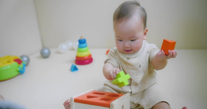 Portrait Of Adorable Happy little Asian baby child Toddler playing with wooden toy blocks on floor living room, Educational game for baby and toddler	
