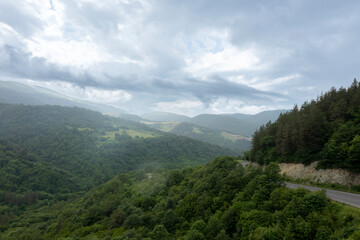Obraz premium Road through a valley from above Aerial view of road through green forest. Wide angle ov view.