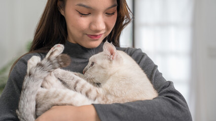 A woman reclining on a couch with her white cat resting on her legs. The setting is relaxed and comfortable