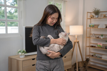 A woman reclining on a couch with her white cat resting on her legs. The setting is relaxed and comfortable