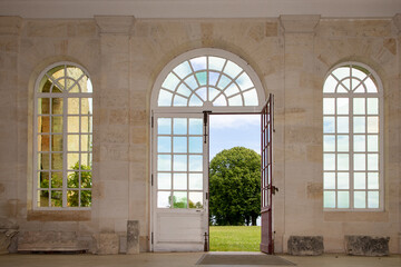 interior room europe with three arch stone windows and wooden door access to park garden in french...