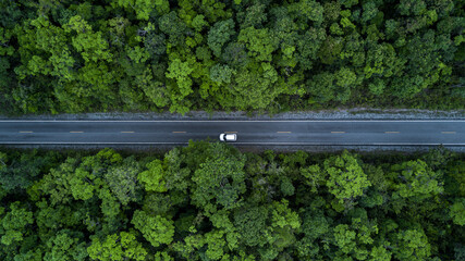 Aerial view electric vehicle car drive on forest road in green tree forest road, EV car electric vehicle car on forest road green energy and eco power, Ev car alternative sustainable renewable energy.