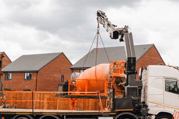 Crane Lifting Cement Mixer During Construction in Residential Neighborhood