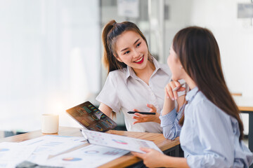 Two businesspeople or an accountant team are analyzing data charts, graphs, and a dashboard on a laptop screen in order to prepare a statistical report and discuss financial data in an office.