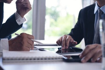 Two businessmen sitting at tbale, using tigital tablet and laptop co-working at modern office, close up. Business colleagues working together, having a discussion on a project