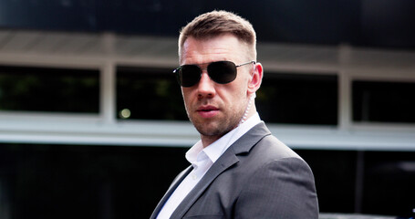 Strong security guard in sunglasses safeguarding entrance with vigilance