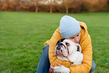 Woman Hugging Bulldog in Park on Cold Day