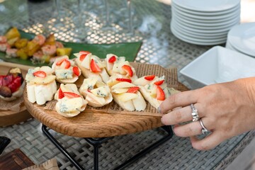 Rustic wooden plate of appetizers with strawberries, cheese, and bread