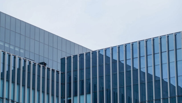 Modern glass office building featuring sleek lines and a reflection of the sky, emphasizing contemporary architectural design.