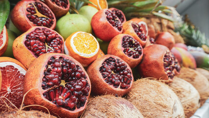 Assorted fresh fruits including pomegranates, oranges, and coconuts.