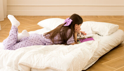 Girl in purple pajamas reading books on bed
