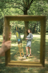 Woman painting on canvas in a picture frame