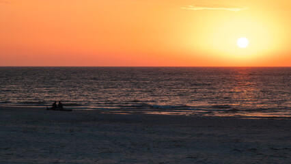 Beautiful sunset over the Baltic Sea. Silhouettes of two people on the beach watching the sunset. Slajszewo, Poland