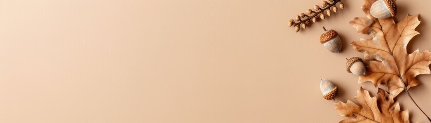 Obraz premium Decorative autumn composition with dry oak leaves, acorns, and wheat on beige background. Perfect for fall season, nature, and harvest themes.
