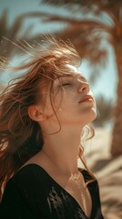 A young woman is captured with her head tilted back, eyes closed, and hair flowing gently in the breeze. The lighting is warm and soft, casting gentle shadows on her face. She is wearing a dark, proba