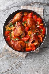 Slow stew rooster in tomato gravy with vegetables close-up in a pan on the table. Vertical top view from above © FomaA