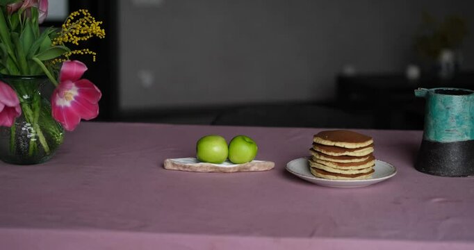 Tasty pancake breakfast with jam and apple. Tea served on a kitchen table. Simple life or perfect morning concept