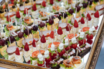 A large selection of various snacks for guests on a mirror surface. Buffet before an important event