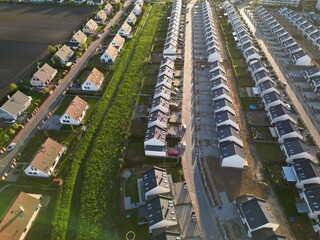 Rows of identical new, single-family houses in a suburban estate, real estate market, modern suburban housing track, aerial view.