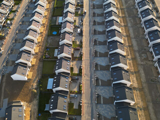 Rows of identical new, single-family houses in a suburban estate, real estate market, modern suburban housing track, aerial view.