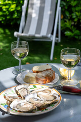 Plate with fresh live oysters with citron, bread, butter and white wine served at restaurant in oyster-farming village, Arcachon bay, Gujan-Mestras port, France