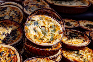 Tasty vegetarian streetfood for lunch in London, various quiche savoury tart swith spinach, tomatoes, mushrooms, cheddar cheese