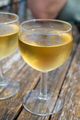 Tasting of Bordeaux white wine in Sauternes, left bank of Gironde Estuary, France. Glasses of white sweet French wine served in outdoor restaurant