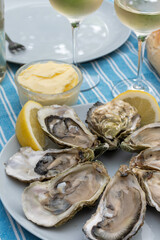 Plate with fresh live oysters with citron, bread, butter and white wine served at restaurant in oyster-farming village, Arcachon bay, Gujan-Mestras port, France