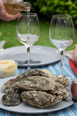 Plate with fresh live oysters with citron, bread, butter and white wine served at restaurant in oyster-farming village, Arcachon bay, Gujan-Mestras port, France