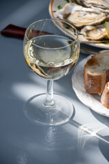 Plate with fresh live oysters with citron, bread, butter and white wine served at restaurant in oyster-farming village, Arcachon bay, Gujan-Mestras port, France
