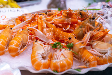 Assortment of fresh daily catch of prawns, seashells, molluscs on ice on fish market in Brittany, France, English translation: differens French names of seafood