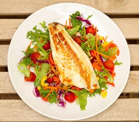 Fried fish fillet over salad