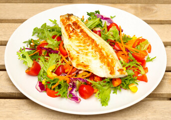 Fried fish fillet over salad