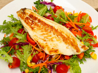 Fried fish fillet over salad