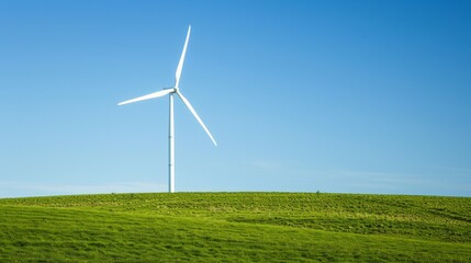 Fototapeta premium A wind turbine stands tall in a grassy field with a bright blue sky