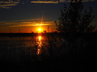 Fototapeta premium Sunset in hues of reddish-orange and yellow over the lake on a summer day.