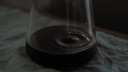 pour over coffee dripping in glass carafe on table with linen cloth