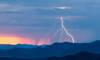 Stunning lightning strike over a mountain range at sunset with vibrant colors in the sky.
