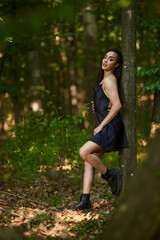 Fototapeta premium Young woman in mini black dress in the forest